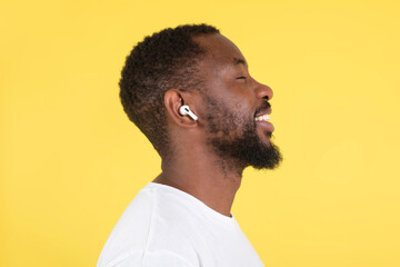 Fototapeta premium Happy African Man Listening Music Wearing Earbuds Over Yellow Background