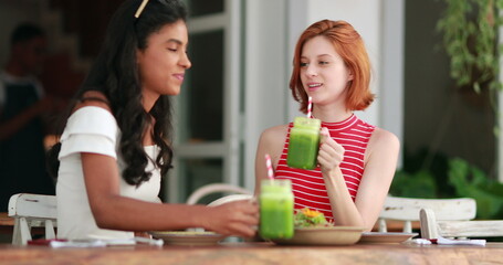 Diversity friendship toasting with healthy green juices, multi-ethnic young women clinking veggie green juice