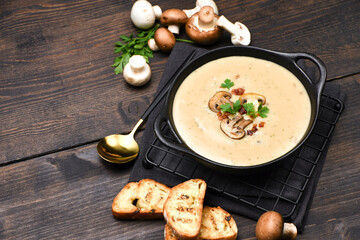 Mushroom soup with bread and fresh mushrooms on a wooden background