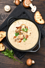Mushroom soup with bread and fresh mushrooms on a wooden background