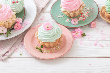 pink and green cupcakes with spring flowers on white wooden background