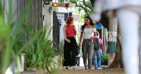 Friends walking together in city sidewalk, diverse multiracial friendship outside