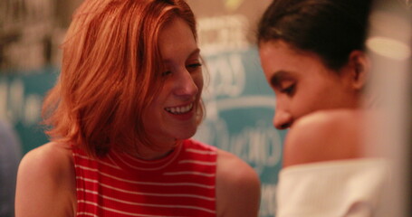 Friend showing cellphone screen to girlfriend at night