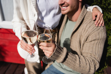 Cropped view of couple in warm cardigans toasting with wine outdoors