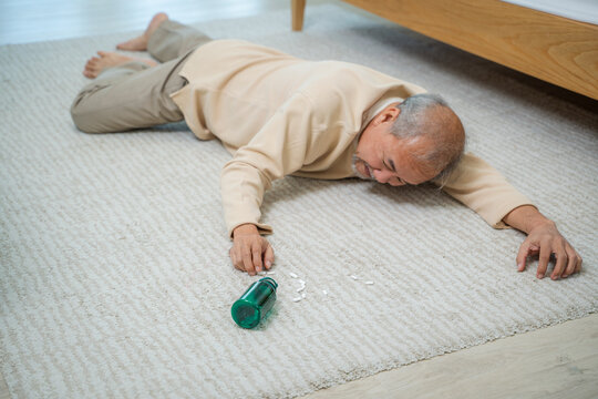 Asian senior man fainting and falling on the ground in the bedroom at home.