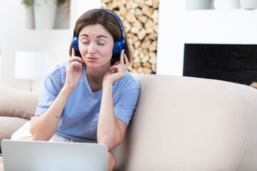 Naklejka premium Young attractive woman in headphones listening to music during break of studying online at home. Distance education concept 