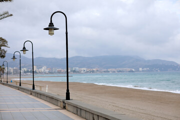 Obraz premium Vintage street lamps on embankment and promenade of resort town. small town surrounded by mountains and Mediterranean sea in Spain, Europe