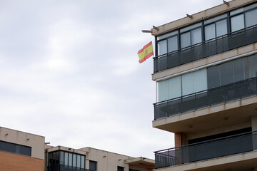 Street view of Benicassim at day with the Spain flag in front of the hotel. hotel building with balconies on the seashore and close to mountains. Vacation concept background.