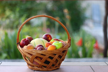 Vintage basket full of seasonal fruit in the garden. Selective focus.