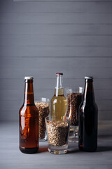 bottles with craft beer  and beer glasses with barley malt on a grey wooden background.  Ale or lager from pilsner malt.  homemade home-brewed beer. - obrazy, fototapety, plakaty