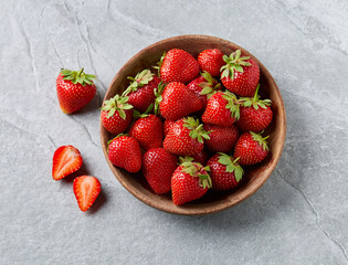 Strawberries in wooden plate on gray background