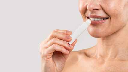 Lips Care. Smiling middle aged woman applying lip balm, closeup shot
