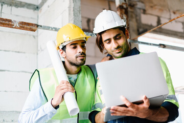 Civil Engineer and Contractor working in vest with safety hardhat using laptop computer while standing and working together on construction site