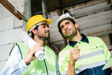 Civil Engineer and Contractor in vest with safety hardhat standing and working side by side on a building site