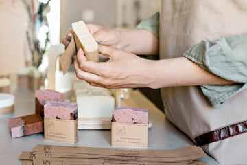 A soap maker girl holds a piece of freshly brewed handmade soap in her hands.The process of...