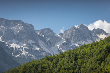 Fototapeta na wymiar stunning high grey mountain with snow fields on a sunny day and blue sky, alpine area 