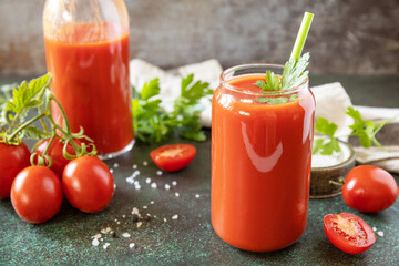Autumn vitamin drink juice tomato. Tomato juice in a glass and fresh tomatoes on a stone tabetop.