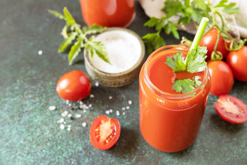 Autumn vitamin drink juice tomato. Tomato juice in a glass and fresh tomatoes on a stone tabetop. Copy space.
