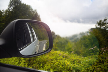 Mountain and road scenery reflected in the rear view mirror