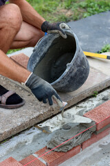 Man works with brick trowel. Masonry work in progress. Wall  made of red bricks texture. 