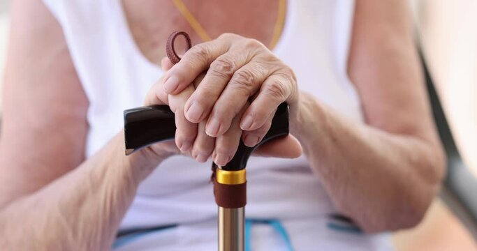 Hands of elderly woman with wooden cane