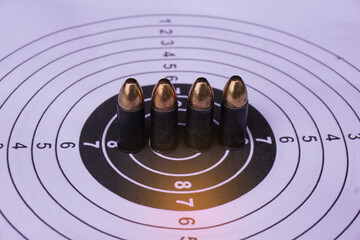 Black 9mm bullets on shooting target paper, soft and selective focus.