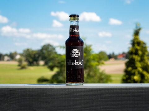 BAUTZEN, GERMANY - 3. September 2022: Fritz Kola bottle in front of a beautiful nature landscape. Serving a chilled beverage as refreshment on a hot summer day. Black sweet drink with caffeine.