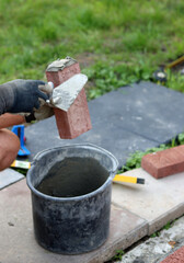Man works with brick trowel. Masonry work in progress. Wall  made of red bricks texture. 