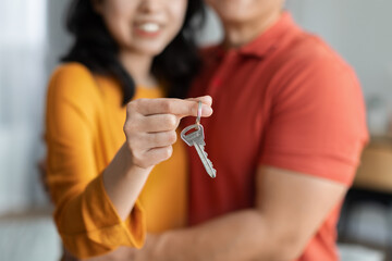 Unrecognizable asian couple hugging together and holding house key