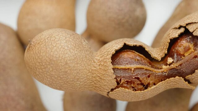 Peeled tamarind rotates against the background of other tamarinds, top view, close-up.