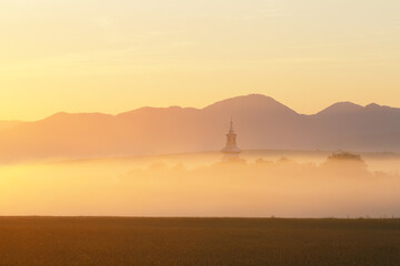 Obraz na płótnie Canvas Church of Pribovce village shrouded in morning fog, Slovakia.
