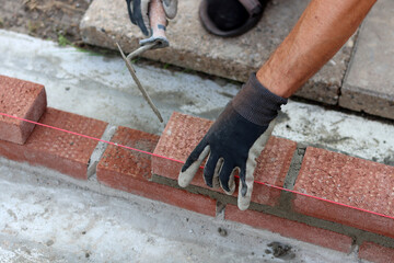 Construction work in progress. Male builder working with red bricks. Masonry wall close up photo.  