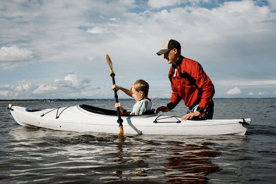 father teaching his son to Kayak in the sea on a sunny day