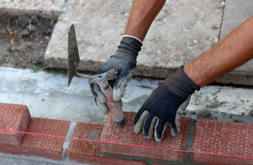 Construction work in progress. Male builder working with red bricks. Masonry wall close up photo.  