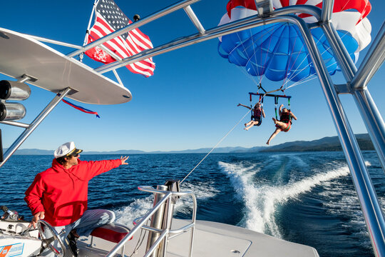 The captain waves as he sends off two women parasailing.