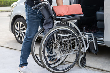 Obraz premium Asian woman folding and lift up wheelchair into her car. Accessibility concept.