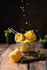 boiled corn cob. with salt and spices. vertical image. for advertising and menus. on a dark background