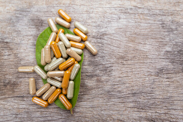 Herbal medicine in capsules from herb leaf on rustic wooden table with copy space for medical background. healthy eating with natural product for good living.