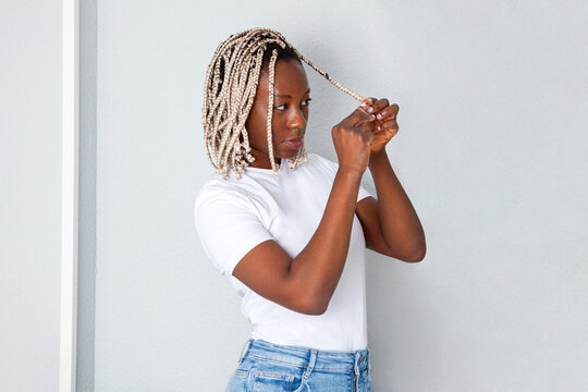 Mujer negra haci&eacute;ndose las trenzas en su casa. Lifestyle