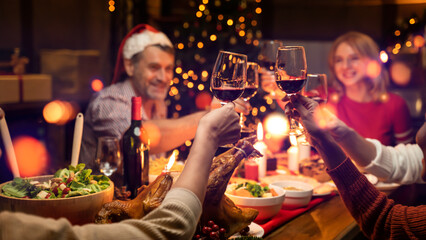 Eve family gathering meeting dream wish concept.Cropped wineglass,cheerful gray-haired grandparents sitting at table, house party,fun joy navidad hands hold glass-Warm filter with focus lower glass
