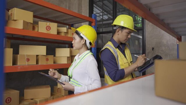 Two male and female employees inspecting the goods in the warehouse for delivery.