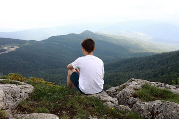 Naklejka na ściany i meble Boy sitting on rock on Lago-Naki plateau in summer
