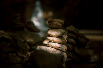 The figure of the stones on the background of the waterfall. The play of light and shadow. Small stones are lined up on top of each other. Stone tower. Light falls on the stones. A beautiful warm even