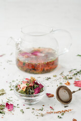 Herbal tea. Detox. Dry tea and brewed tea in a glass teapot on a white wooden background