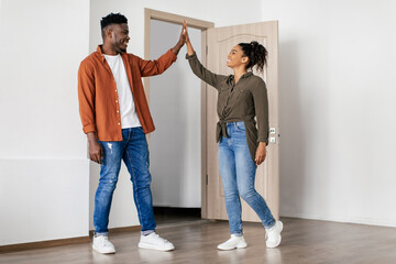 Cheerful Black Couple Giving High Five Standing In New Home