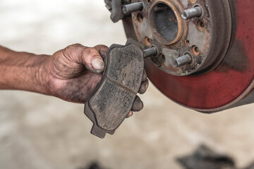 A mechanic showing worn disc brake pads removed from a car. Servicing and replacing old parts of a...