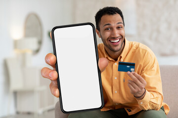 Online Shopping App. Excited black man showing credit card and blank smartphone