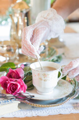 English retro still life and a woman's hand in a white lace glove stirring coffe