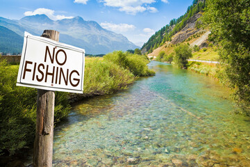 No fishing area - concept with information on road sign against a stream of water