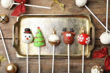 Delicious Christmas themed cake pops on wooden table, flat lay